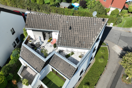 Eine Vogelperspektive zeigt ein Haus mit dem Fokus auf das Dach, wahrscheinlich aufgenommen von einer Drohne aus.